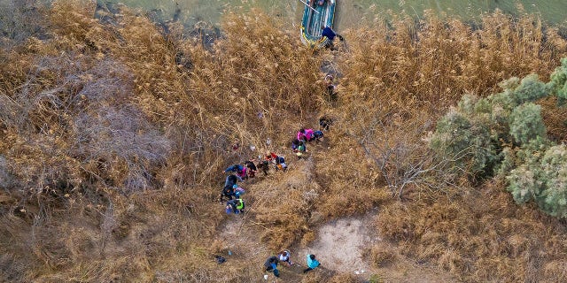 Migrant families and children climb the banks of the Rio Grande to the United States as raft smugglers prepare to return to Mexico in Penitas, Texas, United States, March 5, 2021. 