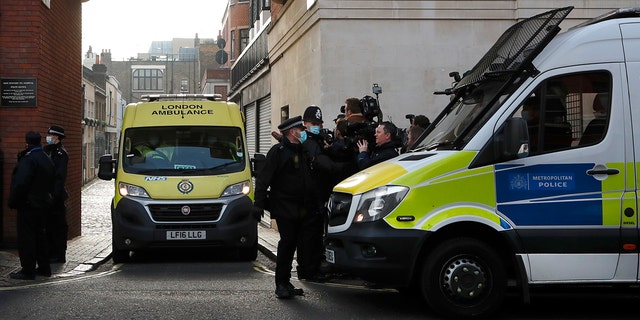 Police officers stand at an entrance to the King Edward VII Hospital where Prince Philip is being treated for an infection, as an ambulance is driven out, in London, Monday, March 1, 2021.