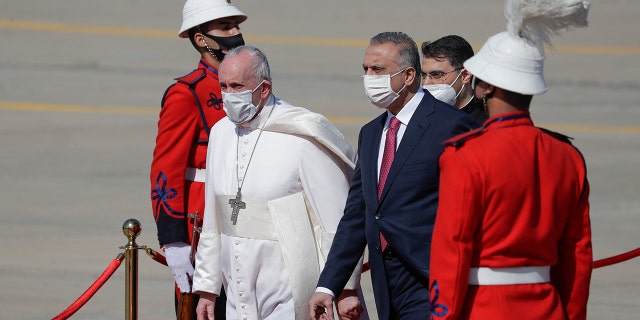 Pope Francis is flanked by Iraqi Prime Minister Mustafa al-Kadhimi upon his arrival at Baghdad's international airport, Iraq, Friday, March 5, 2021. Pope Francis heads to Iraq on Friday to urge the country's dwindling number of Christians to stay put and help rebuild the country after years of war and persecution, brushing aside the coronavirus pandemic and security concerns. (AP Photo/Andrew Medichini)