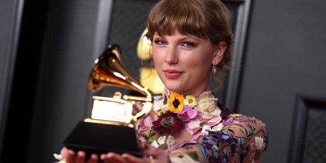 Taylor Swift poses in the press room with the award for album of the year for "Folklore" at the 63rd annual Grammy Awards at the Los Angeles Convention Center March 14, 2021. 