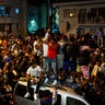 Crowds defiantly gather in the street while a speaker blasts music an hour past curfew in Miami Beach, Florida, on Sunday, March 21, 2021. An 8 p.m. curfew has been extended in Miami Beach after law enforcement worked to contain unruly crowds of spring break tourists. (Daniel A. Varela/Miami Herald via AP)