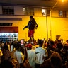 A man stands on a car as crowds defiantly gather in the street while a speaker blasts music an hour past curfew in Miami Beach, Florida, on Sunday, March 21, 2021. An 8 p.m. curfew has been extended in Miami Beach after law enforcement worked to contain unruly crowds of spring break tourists. (Daniel A. Varela/Miami Herald via AP)