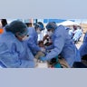 Baja California state health workers take heath readings of a toddler at a makeshift camp for migrants seeking asylum in the United States at the border crossing Friday, March 12, 2021, in Tijuana, Mexico. The Biden administration hopes to relieve the strain of thousands of unaccompanied children coming to the southern border by terminating a 2018 Trump-era order that discouraged potential family sponsors from coming forward to house the children. (AP Photo/Gregory Bull)