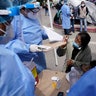 A woman speaks to Baja California state health workers at a makeshift camp at the border port of entry leading to the United States, Friday, March 12, 2021, in Tijuana, Mexico. The migrant camp shows how confusion has undercut the message from President Joe Biden that it’s not the time to come to the United States. Badly misinformed, some 1,500 migrants set up tents across the border from San Diego harbor in the hope that Biden will open entry briefly and without notice. (AP Photo/Gregory Bull)