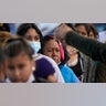 Migrant women are asked to line up for a free meal at a makeshift camp at the border port of entry leading to the United States on Friday, March 12, 2021, in Tijuana, Mexico. The migrant camp shows how confusion has undercut the message from President Joe Biden that it’s not the time to come to the United States. Badly misinformed, some 1,500 migrants set up tents across the border from San Diego harbor in the hope that Biden will open entry briefly and without notice. (AP Photo/Gregory Bull)