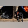 A boy sits in front of a tent housing several families at a makeshift camp of migrants at the border port of entry leading to the United States, Wednesday, March 17, 2021, in Tijuana, Mexico. The migrant camp shows how confusion has undercut the message from President Joe Biden that it’s not the time to come to the United States. Badly misinformed, some 1,500 migrants set up tents across the border from San Diego harbor in the hope that Biden will open entry briefly and without notice. (AP Photo/Gregory Bull)