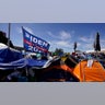 A donated campaign flag for President Joe Biden flies over tents at a makeshift camp of migrants at the border port of entry leading to the United States, Wednesday, March 17, 2021, in Tijuana, Mexico. The migrant camp shows how confusion has undercut the message from Biden that it’s not the time to come to the United States. Badly misinformed, some 1,500 migrants set up tents across the border from San Diego harbor in the hope that Biden will open entry briefly and without notice. (AP Photo/Gregory Bull)