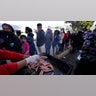 Migrants line up for a free meal donated by a local church at a makeshift camp at the border port of entry leading to the United States, Wednesday, March 17, 2021, in Tijuana, Mexico. The migrant camp shows how confusion has undercut the message from President Joe Biden that it’s not the time to come to the United States. Badly misinformed, some 1,500 migrants set up tents across the border from San Diego harbor in the hope that Biden will open entry briefly and without notice. (AP Photo/Gregory Bull)
