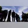 Migrants line up for a free meal at a makeshift camp at the border port of entry leading to the United States, Wednesday, March 17, 2021, in Tijuana, Mexico. The migrant camp shows how confusion has undercut the message from President Joe Biden that it’s not the time to come to the United States. Badly misinformed, some 1,500 migrants set up tents across the border from San Diego harbor in the hope that Biden will open entry briefly and without notice. (AP Photo/Gregory Bull)