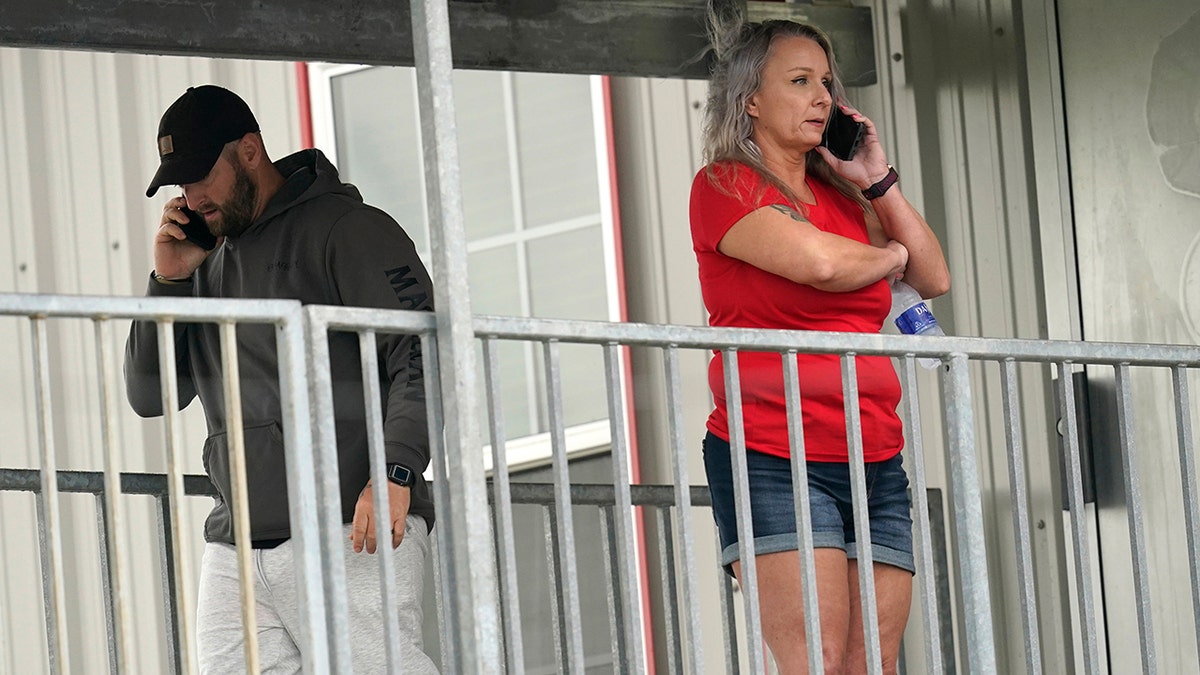 Marion Cuyler, right, fiancée of missing crew member Chaz Morales, and an unidentified man, talk on their phones Thursday at a fire station where family members of 12 people missing from a capsized oil industry vessel have been gathering, in Port Fourchon, La. (AP)