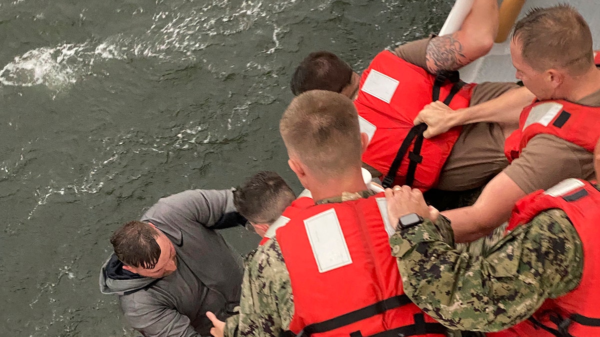 Crew members of the Coast Guard Cutter Glenn Harris pull a person from the water on Tuesday, April 13, 2021 after a commercial lift boat capsized 8 miles south of Grand Isle, La. (AP/U.S. Coast Guard)