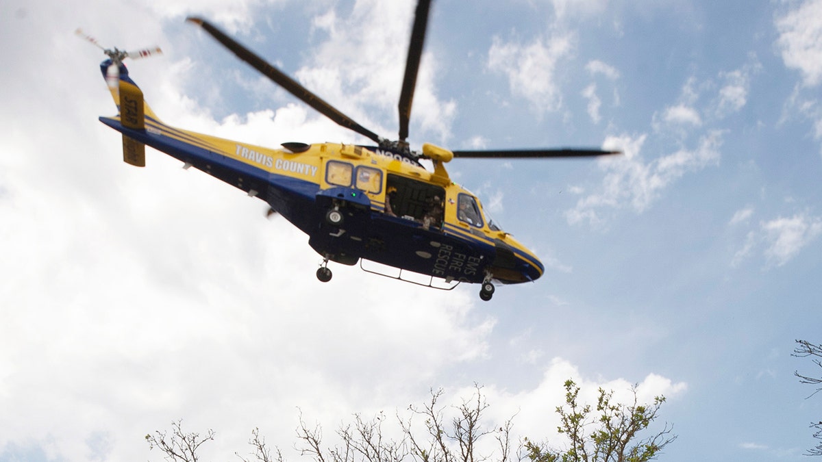 An Austin police officer holds his hat to keep it from flying away in the backwash of a helicopter that took off near the Arboretum Oaks apartment complex, the scene of a deadly shooting in Austin, Texas, April 18, 2021. (REUTERS/Nuri Vallbona)