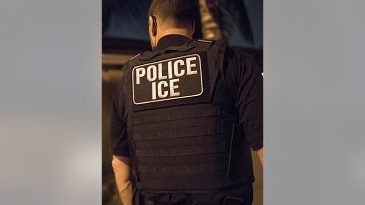 Agente do ICE visto por trás com "GELO DA POLÍCIA" etiqueta nas costas da camisa