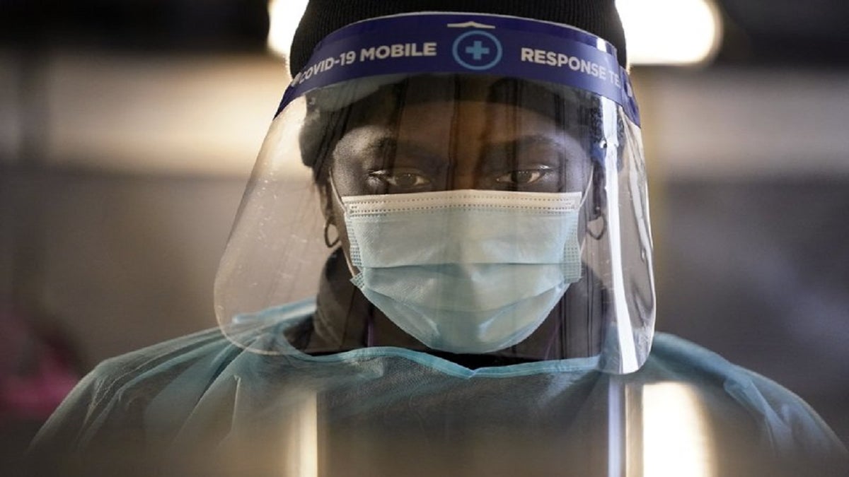In this Dec. 8, 2020, file photo, a health care worker wears personal protective equipment as she speaks to a patient at a mobile testing location for COVID-19 in Auburn, Maine. (AP Photo/Robert F. Bukaty, File)