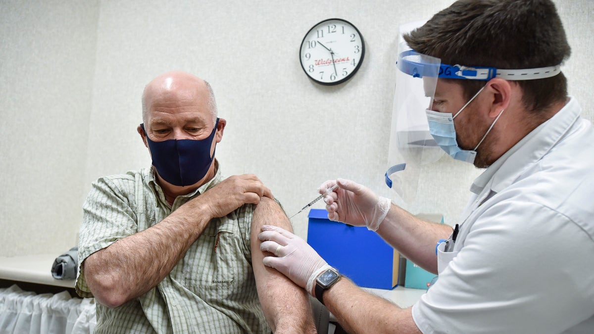 Gov. Greg Gianforte receives a shot of the Pfizer COVID-19 vaccine from pharmacist Drew Garton at a Walgreen's pharmacy, Thursday, April 1, 2021, in Helena, Montana.  (Thom Bridge/Independent Record via AP)