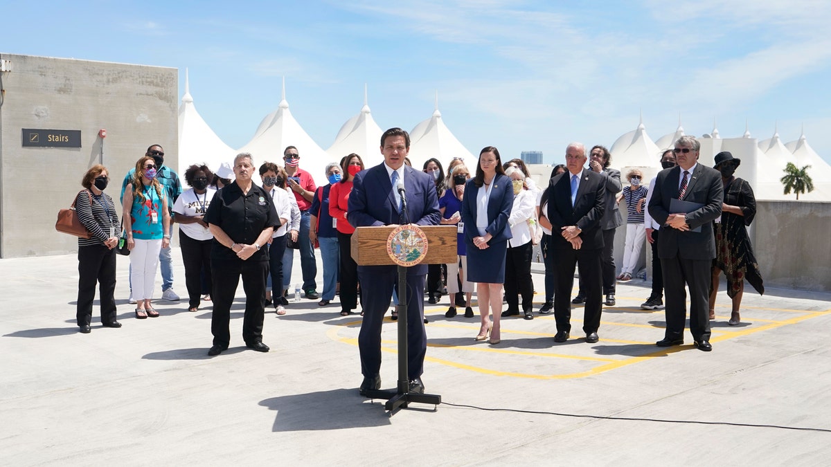 Florida Gov. Ron DeSantis, center, speaks during a news conference surrounded by cruise workers on April 8 at the Port of Miami in Miami. DeSantis announced a lawsuit against the federal government and the CDC demanding that cruise ships be allowed to sail. (AP Photo/Wilfredo Lee)