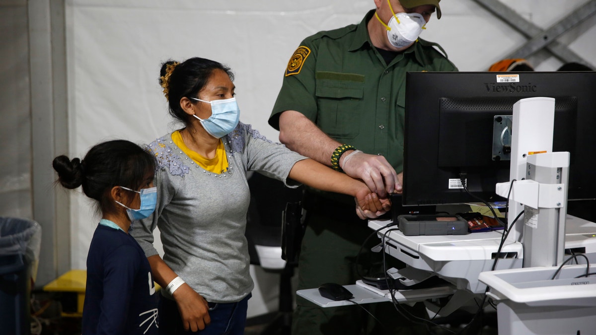 A migrant and her daughter are processed at a DHS detention facility in 2021
