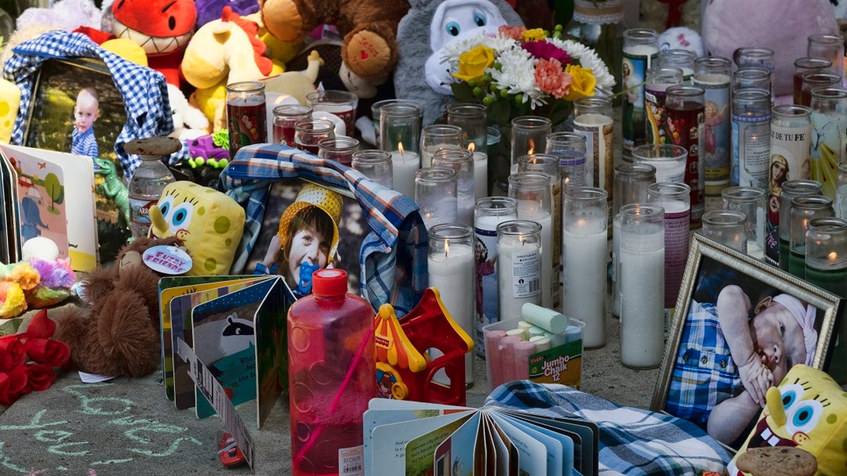 Photos, candles, flowers and balloons are placed as a memorial for three children who were killed at the Royal Villa apartments complex in the Reseda section of Los Angeles. Authorities have identified 3-year-old Joanna Denton Carrillo, her 2-year-old brother, Terry, and 6-month-old sister, Sierra. (AP Photo/Richard Vogel)