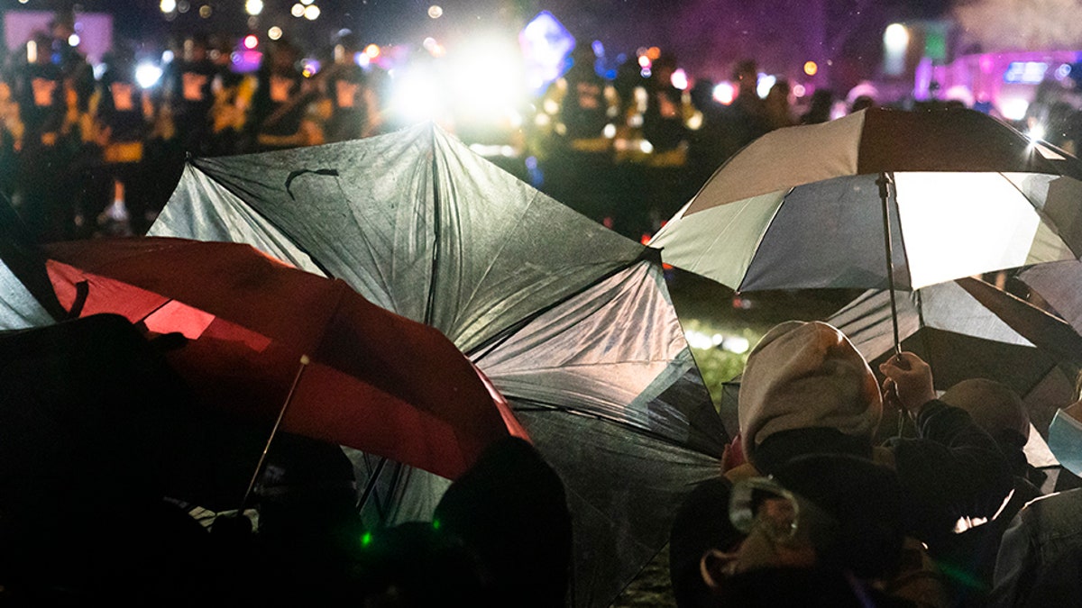 Demonstrators use umbrellas as shields against police during a clash outside the Brooklyn Center Police Department while protesting the shooting death of Daunte Wright, late Tuesday, April 13, 2021, in Brooklyn Center, Minn. (AP Photo/John Minchillo)