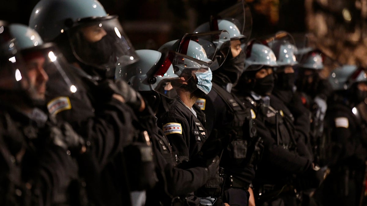 Police officers look on near Chicago Mayor Lori Lightfoot's home as people protest the shooting and killing of 13-year-old Adam Toledo by an officer Friday, April 16, 2021, in Chicago. (AP Photo/Paul Beaty)