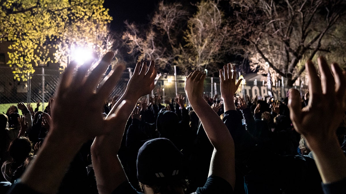 Demonstrators hold their hands up toward authorities stationed behind a perimeter security fence, during a protest over the fatal shooting of Daunte Wright by a police officer during a traffic stop, outside the Brooklyn Center Police Department, Saturday, April 17, 2021, in Brooklyn Center, Minn. (AP Photo/John Minchillo)