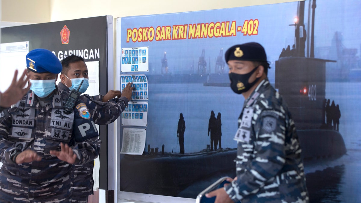 An Indonesian military official sets pictures of Indonesian Navy members on submarine KRI Nanggala that went missing while participating in a training exercise on Wednesday, at Ngurah Rai Airport, Bali, Indonesia, on Friday, April 23, 2021. (AP Photo/Firdia Lisnawati)