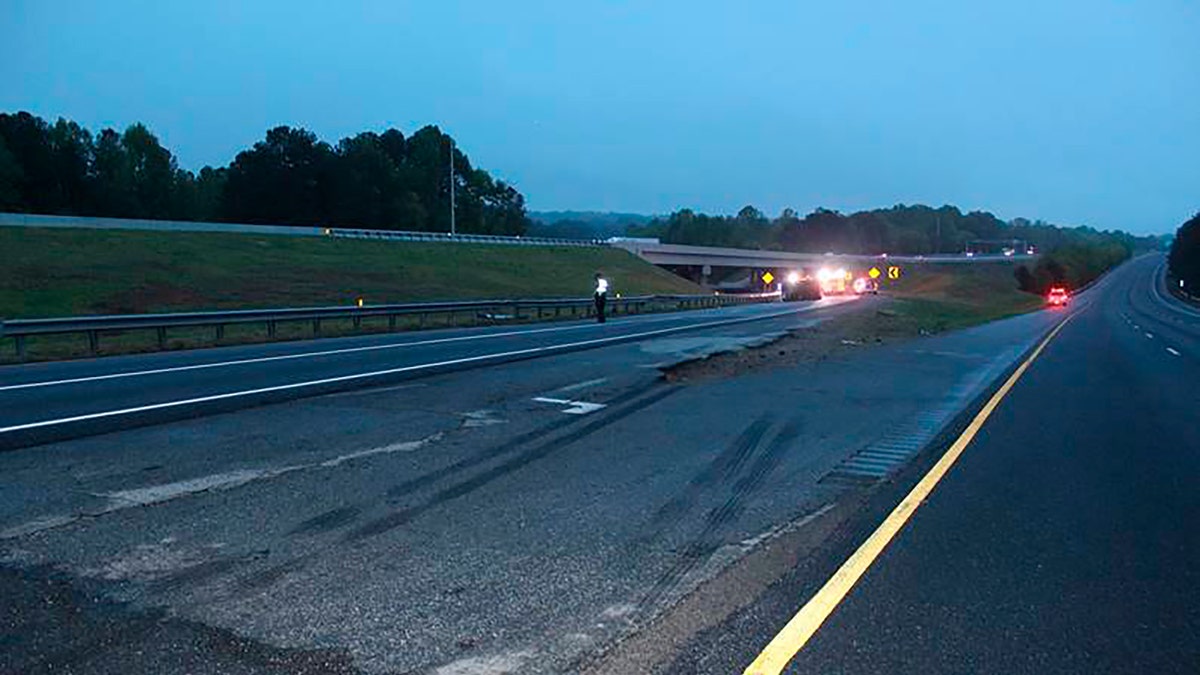 This photo provided by the Gwinnett County Police Department shows tire marks on the pavement, front, near the scene of a deadly crash in Gwinnett County, Ga., Saturday, April 24. 2021. Police in Georgia say multiple people died and several others were hurt in the interstate crash. Gwinnett County police say the crash left a passenger van engulfed in flames and rolled on its side Saturday evening. (Gwinnett County Police Department via AP)