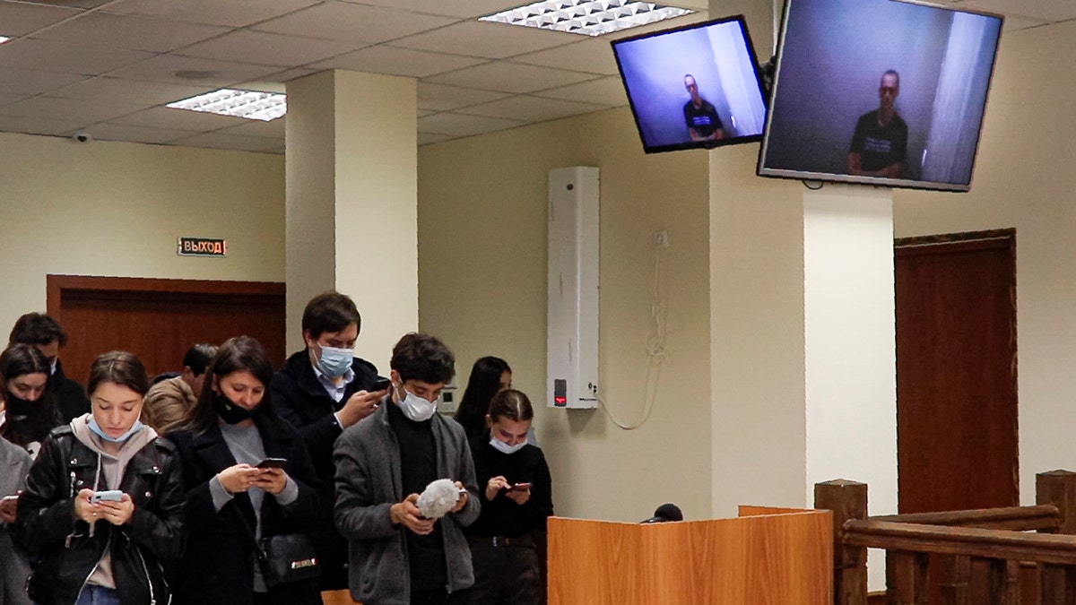 In this photo provided by the Babuskinsky District Court on Thursday, April 29, 2021, Russian opposition leader Alexei Navalny appears on TV screens via a video link from prison, during a hearing on his charges for defamation, in the Babuskinsky District Court in Moscow, Russia. (Babuskinsky District Court Press Service via AP)