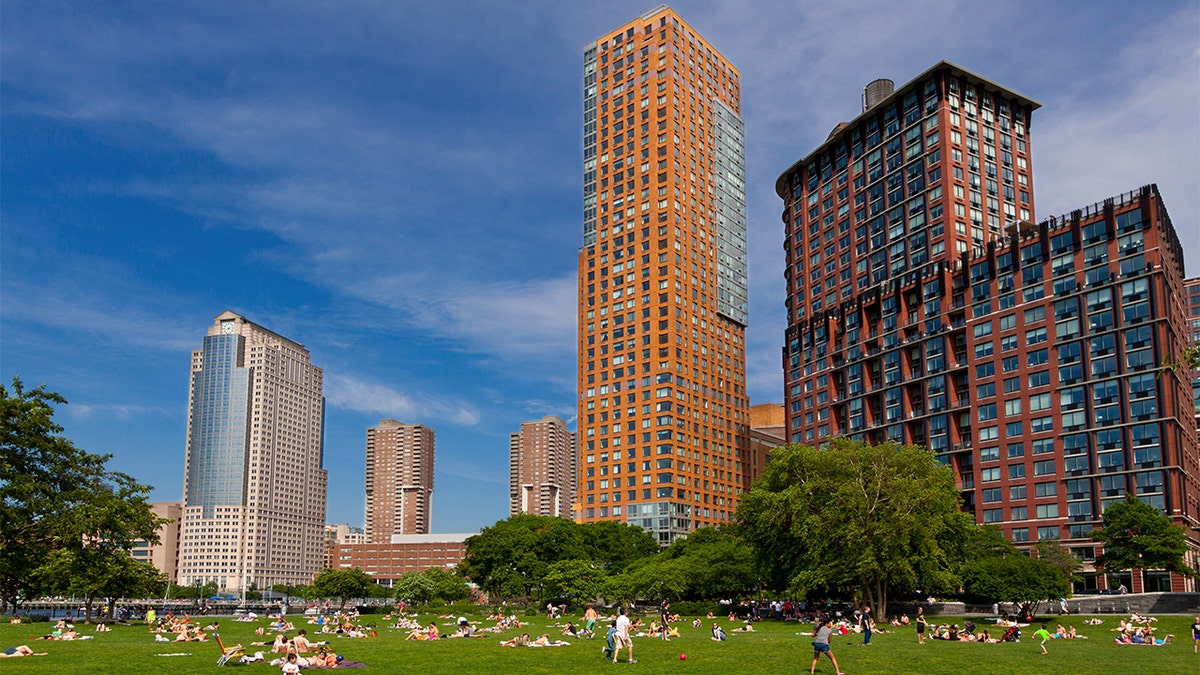 Battery Park City with Citygroup building (on the left) in background, Lower Manhattan, New York City. People are relaxing and enjoying a beautiful summer day outside. Wide angle lens.