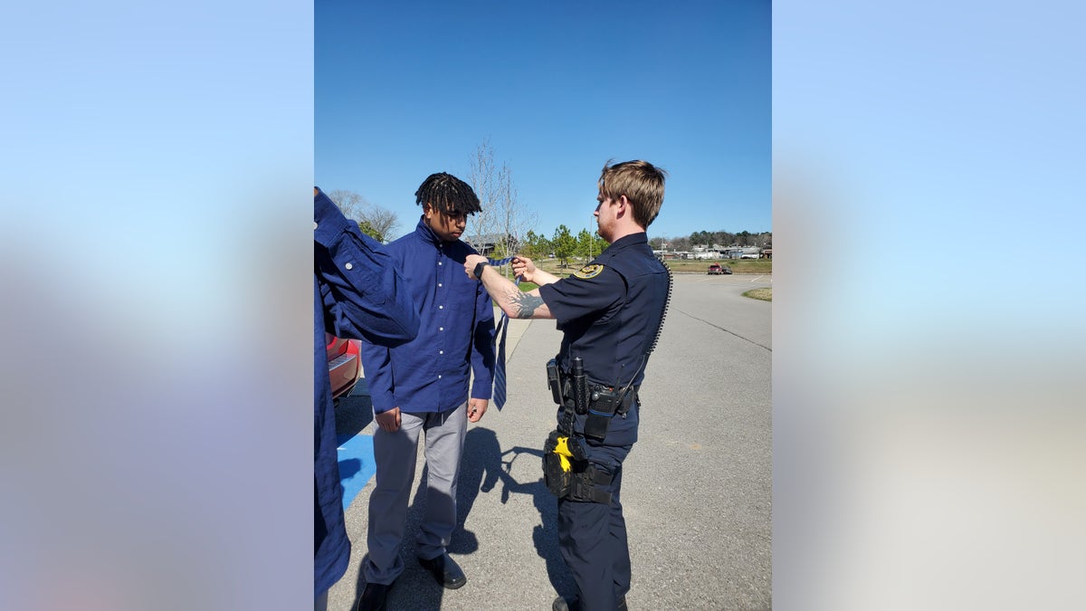 Officer Adam Price helps 18-year-old Elijah Darling tie a tie.