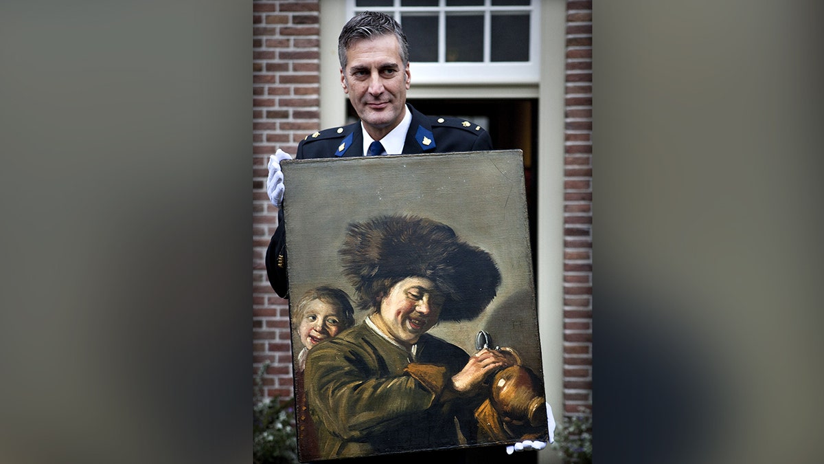 This photograph taken on November 3, 2011, shows District Chief of Alblasserwaard, Bart Willemsen showing the recovered painting "Two Laughing Boys" by Frans Hals which was stolen from the Leerdam Museum in May 2011. (Photo by ILVY NJIOKIKTJIEN/ANP/AFP via Getty Images)