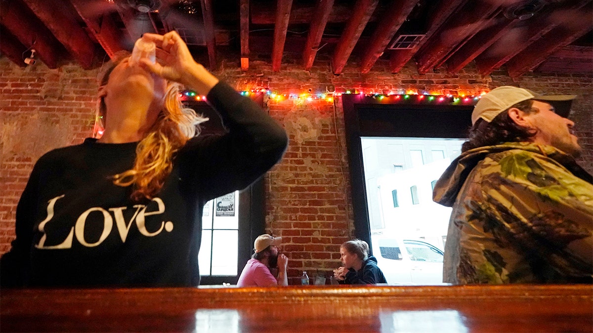 In this Tuesday, April 13, 2021 file photo, Allison Richter drinks her free shot at the bar, after receiving the Moderna COVID-19 vaccine, during a vaccine event. (AP Photo/Gerald Herbert)