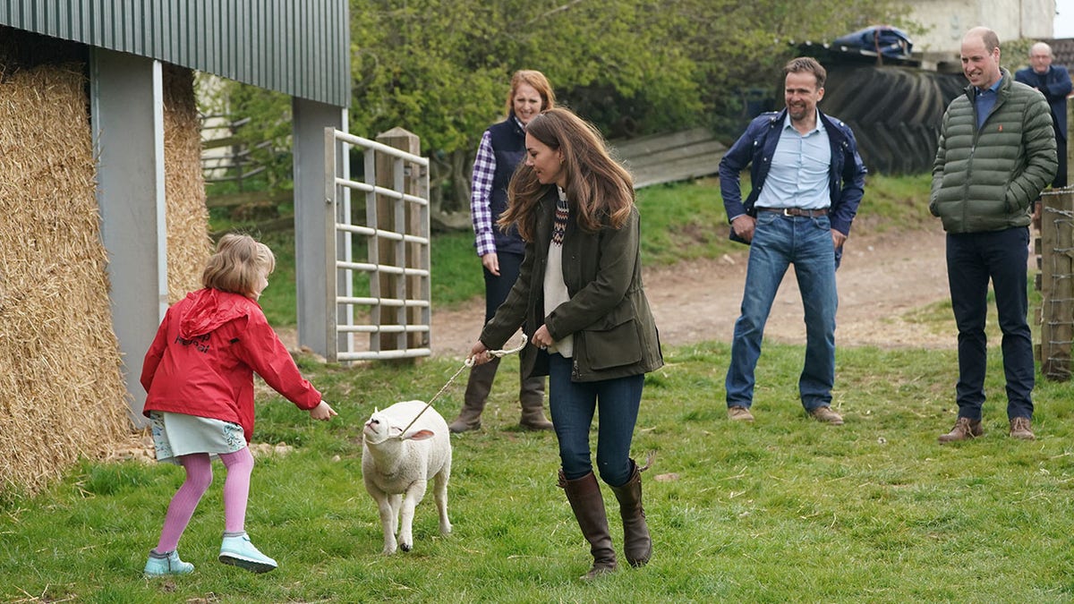 Catherine, Duchess of Cambridge and farmer's daughter Clover Chapman, 9, walk a lamb together, watched by her parents and Prince William, Duke of Cambridge, during a royal visit to Manor Farm in Little Stainton, Durham on April 27, 2021, in Darlington, England.