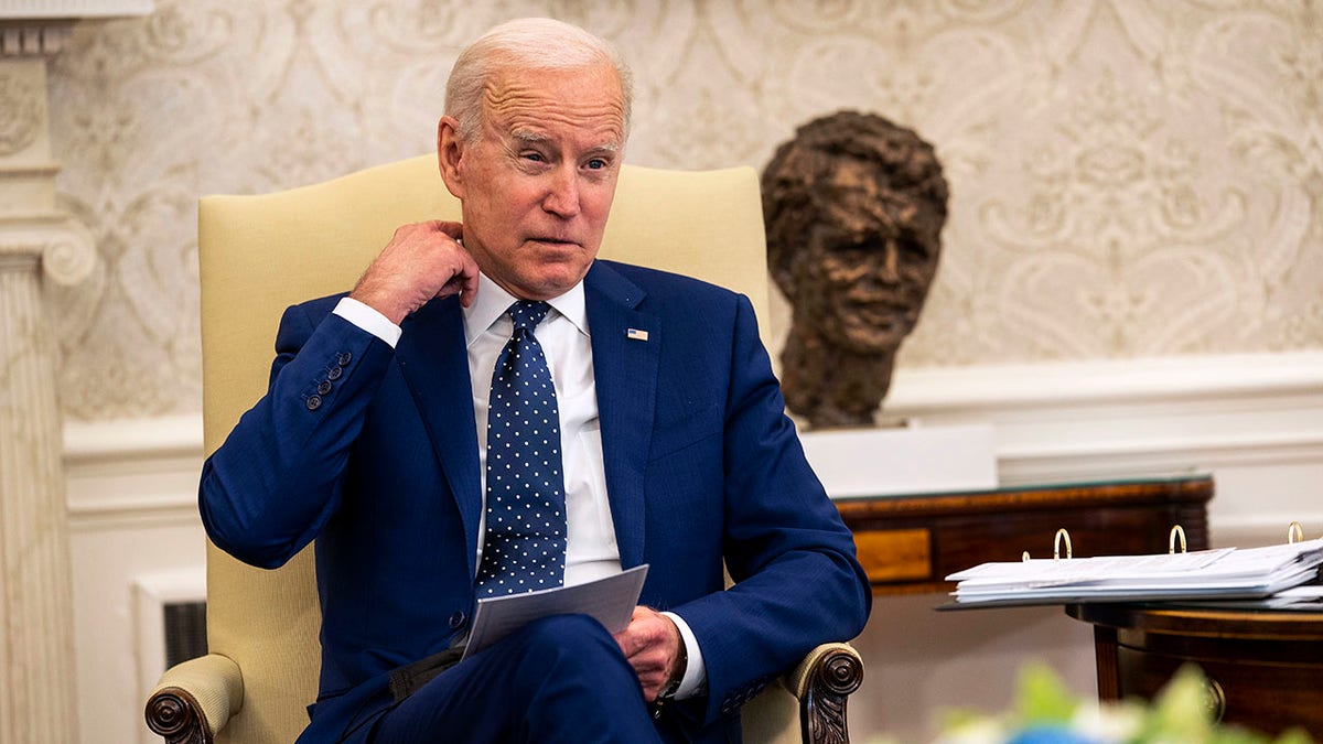 A seated President Biden tugs astatine his collar