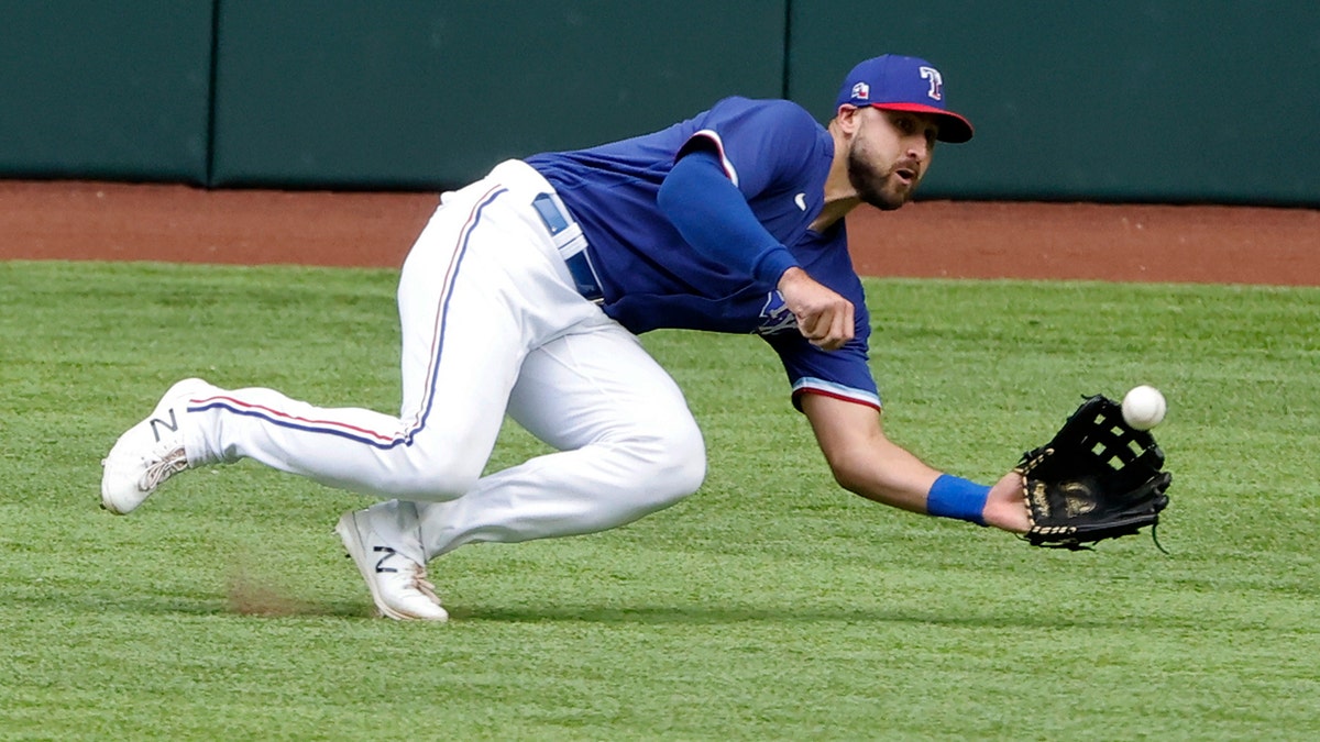 Texas Rangers center fielder Joey Gallo makes a diving catch against the Milwaukee Brewers during the third inning of a preseason baseball game Tuesday, March 30, 2021, in Arlington, Texas. (AP Photo/Michael Ainsworth)