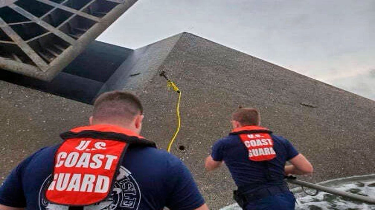 Coast Guard Station Grand Isle 45-foot Response Boat-medium boat crew members attempt to throw a hammer Thursday at the hull of the SeaCor Power. The crew was attempting to make contact with potential survivors inside the vessel. (AP/U.S. Coast Guard)