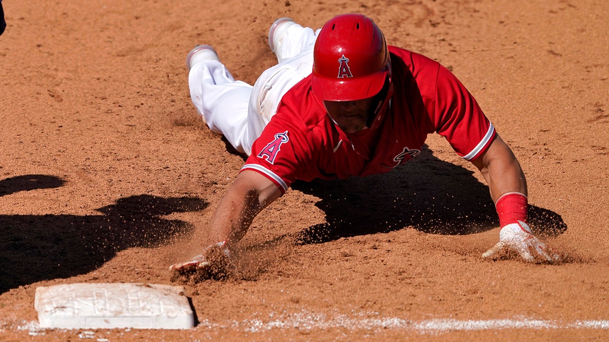 Los Angeles Angels' Mike Trout dives back safely on a pick-off attempt during the fifth inning of a spring training baseball game against the Milwaukee Brewers, Thursday, March 18, 2021, in Tempe, Ariz. (AP Photo/Matt York)