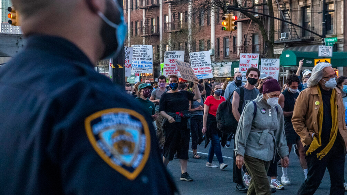 Police officers keep a watchful eye as peaceful protesters march down Flatbush Avenue on Tuesday, April 20, 2021, in the Brooklyn borough of New York. 