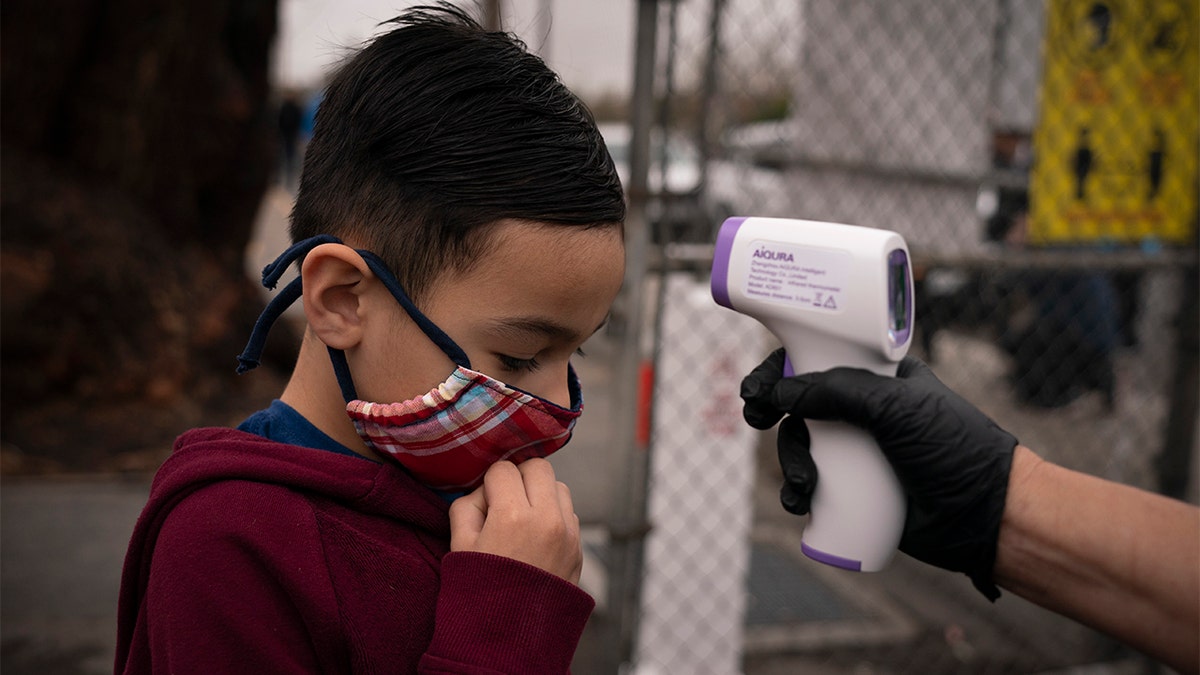 Adam Alvarado, 6, gets his temperature checked on the first day of in-person learning at Heliotrope Avenue Elementary School in Maywood, Calif., Tuesday, April 13, 2021. (AP Photo/Jae C. Hong)