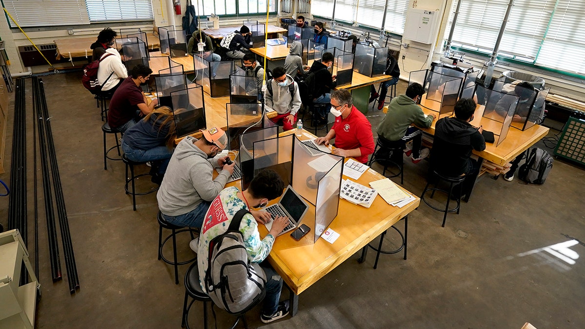 Wyandotte County High School are separated by plastic dividers on the first day of in-person learning at the school in Kansas City, Kan. (AP Photo/Charlie Riedel, File)