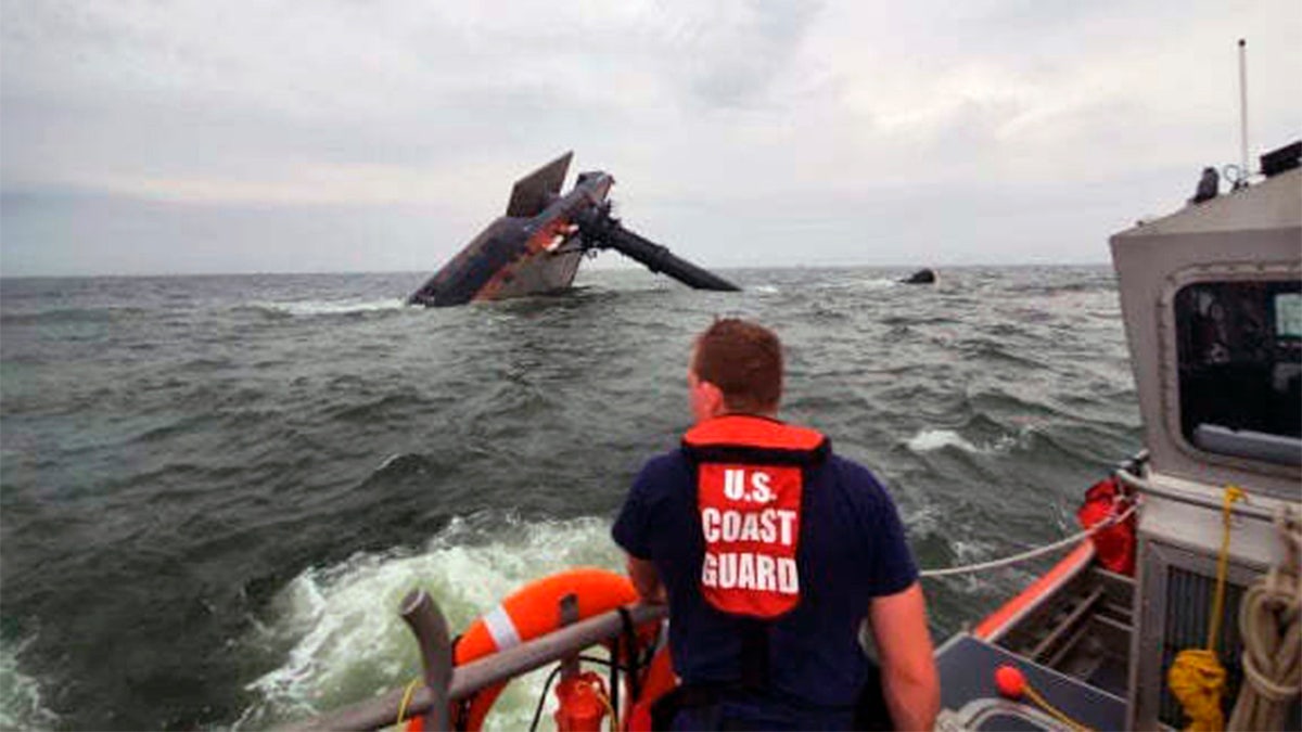 In this photo provided by the U.S. Coast Guard, A Coast Guard Station Grand Isle 45-foot Response Boat-medium boat crew member searches for survivors near the capsized SeaCor Power. The Seacor Power, an oil industry vessel, flipped over Tuesday, April 13, 2021 in a microburst of dangerous wind and high seas. (U.S. Coast Guard via AP)