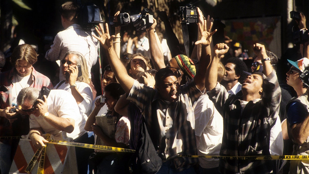 The crowd cheers after hearing the decision of the O.J. Simpson verdict at the Los Angeles Courthouse on October 3, 1995. (Photo by Michael Montfort/Michael Ochs Archives/Getty Images)