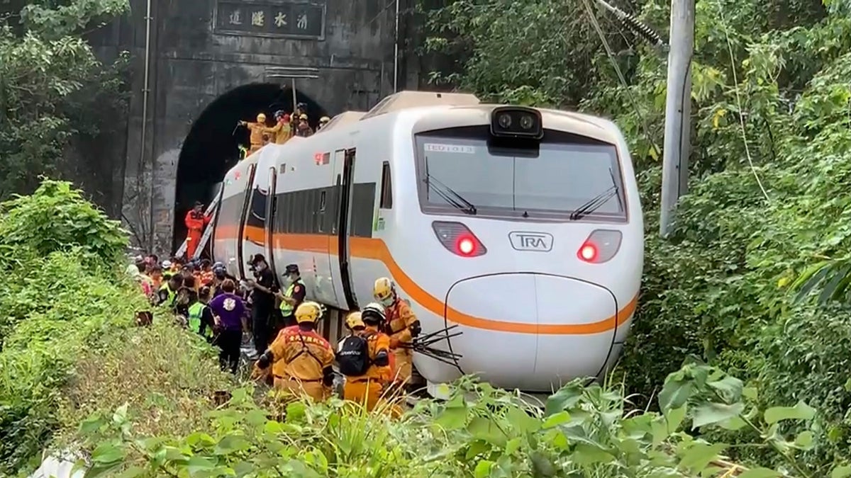 Rescue workers gather near one end of the train involved in a derailment. (AP/Executive Yuan)