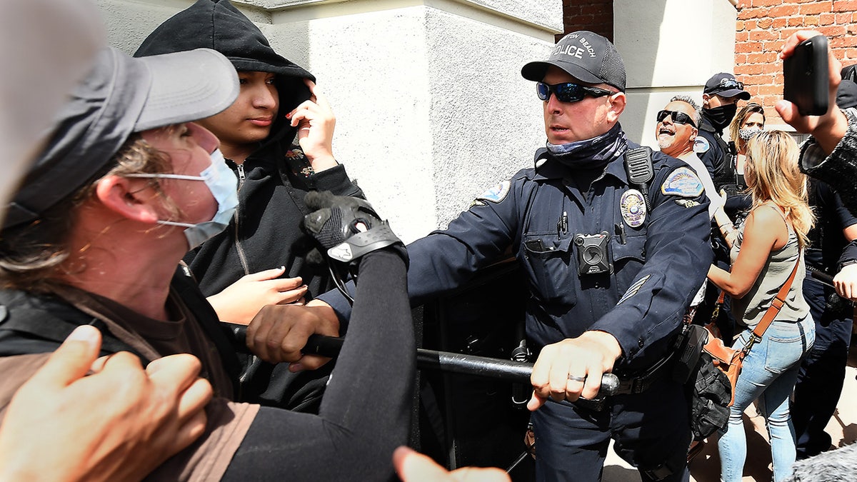 HUNTINGTON BEACH, CALIFORNIA APRIL 11, 2021-Huntington Beach police officers try to seperate supporters during a Black Lives Matter and White Lives Matter rally in Huntington Beach Sunday.(Wally Skalij/Los Angeles Times via Getty Images)