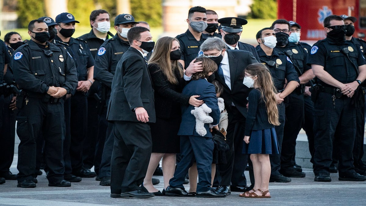 Family members hug after the casket of Evans was carried from the Capitol on Tuesday. (AP/The Washington Post)