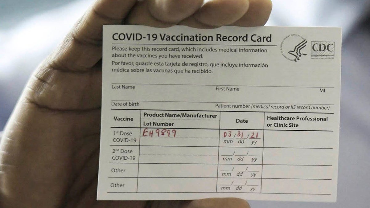 Dr. Leon Haley Jr. the CEO of UF Health Jacksonville shows his COVID-19 vaccination record card shortly before he received the first injection of the COVID-19 vaccine. (Bob Self/Florida Times-Union via AP)