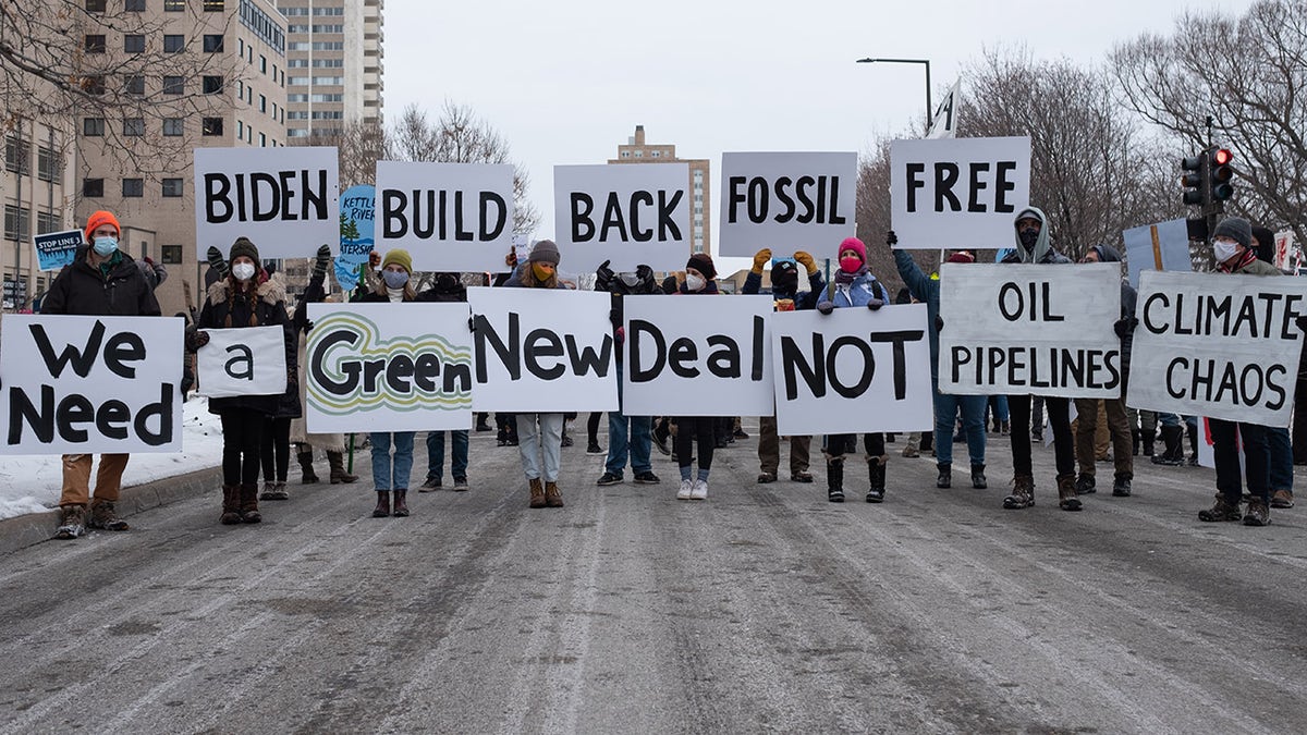 People hold signs calling for President Joe Biden to support a Green New Deal and end his support of pipelines and the fossil fuel industry. St. Paul, MN. January 29, 2021. 