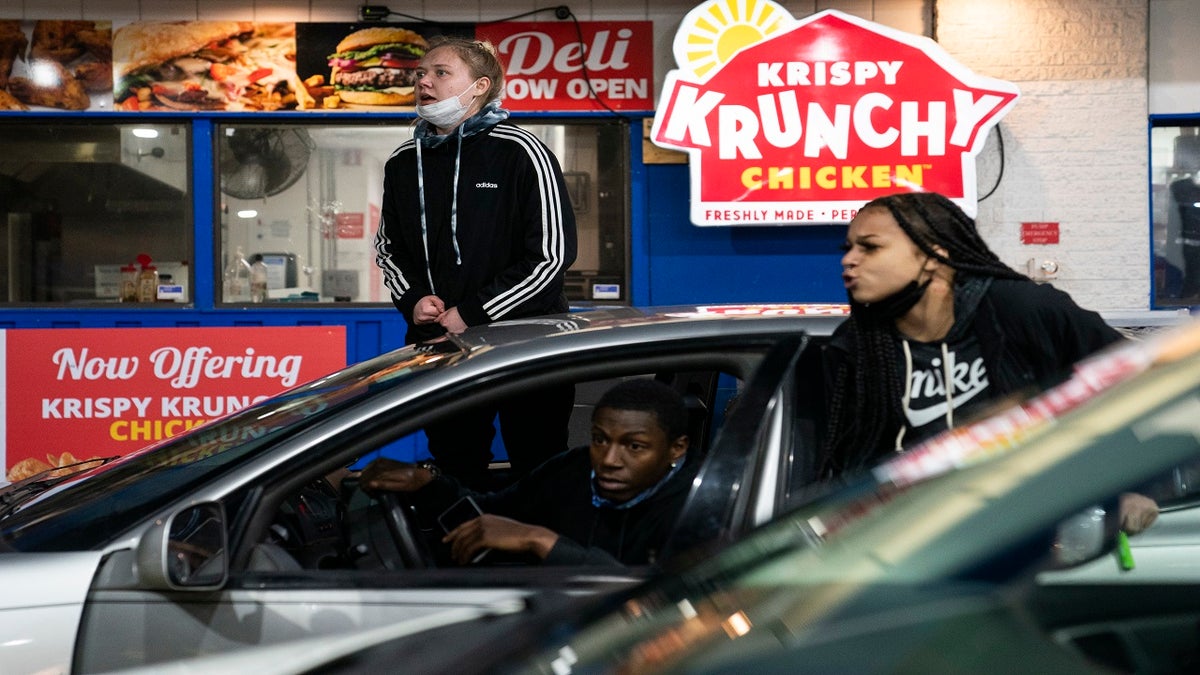 Drivers react as a line of police advances into a gas station in an effort to push back demonstrators gathered for a protest against the police shooting of Daunte Wright, late Monday, in Brooklyn Center, Minn. (AP)