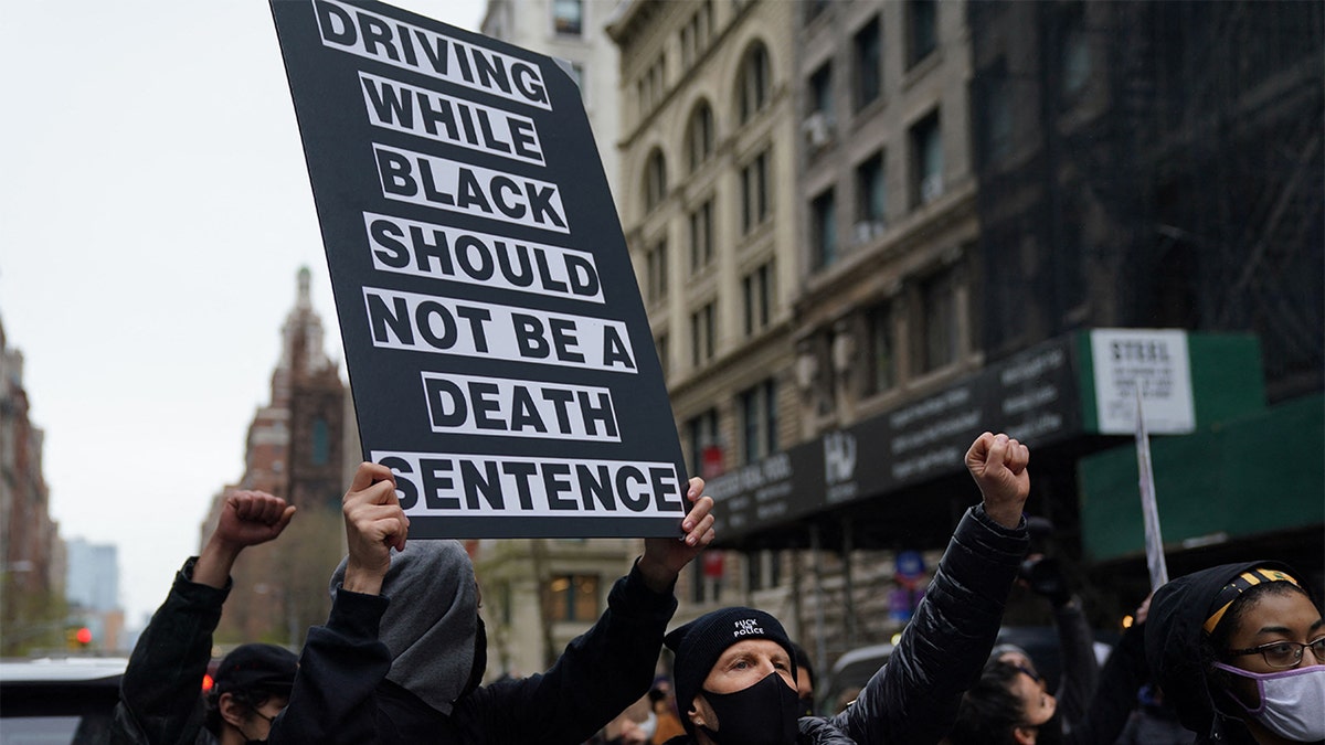 Protesters holding a sign saying "driving while black should not be a death sentence"