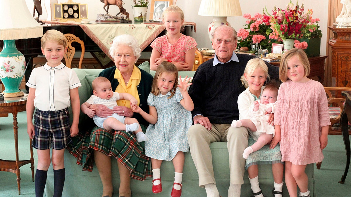 In this undated handout photo provided by the Duke and Duchess of Cambridge, Britain's Queen Elizabeth and Prince Philip with their great grandchildren, from left, Prince George, Prince Louis, Savannah Phillips (standing at rear), Princess Charlotte, Isla Phillips holding Lena Tindall, and Mia Tindall. Britain's Prince Philip, the irascible and tough-minded husband of Queen Elizabeth II who spent more than seven decades supporting his wife in a role that mostly defined his life, died on Friday, April 9, 2021.